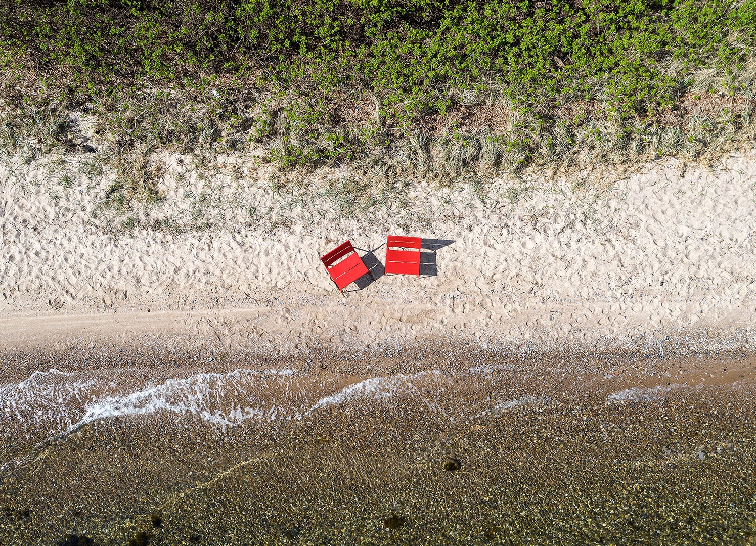 Två röda TERÄS solstolar på stranden