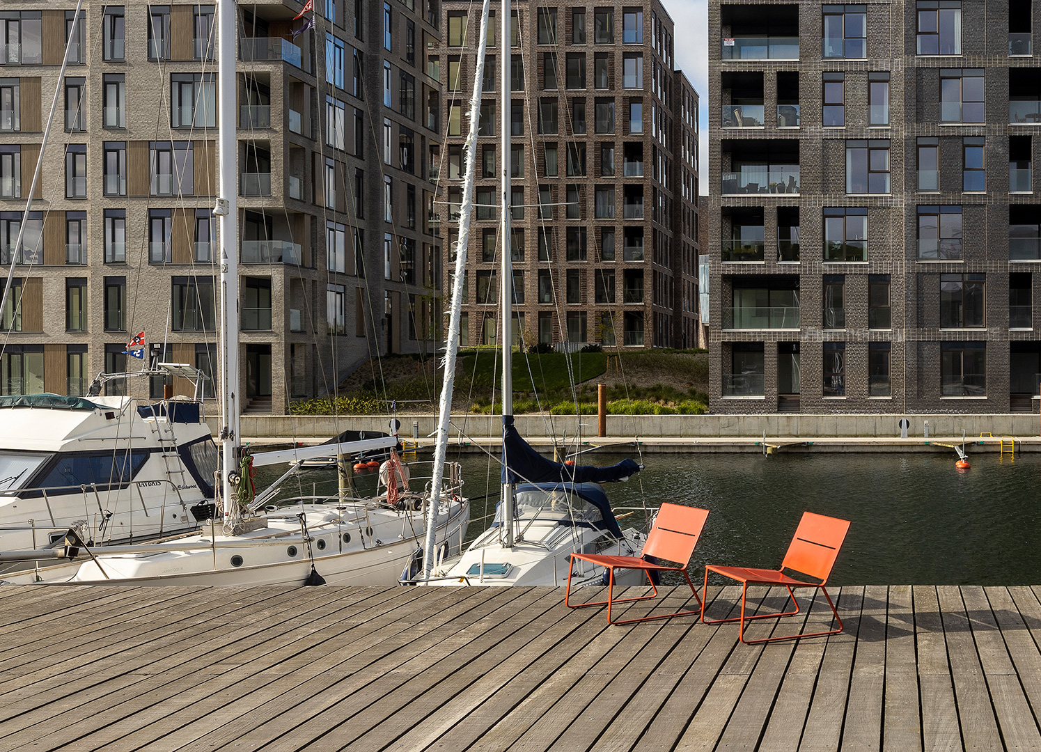 Orange solstolar i modern dansk design syns vid hamn